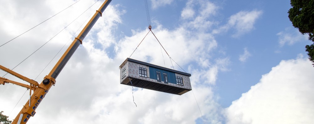 A crane on a construction site lifts a modular component into place. 